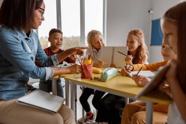 Gülümseyen kızlar ellerinde defter tutup öğretmenlerine gösteriyorlar.