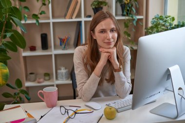 Gülümseyen güzel bayan odada bilgisayarın önünde oturuyor.