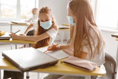 Sınıfta kalem ve defter kullanan kızlar.