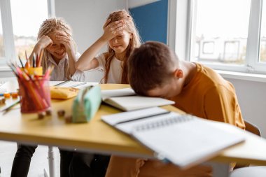 Okulda sınıf arkadaşlarının yanında oturan iki kız.