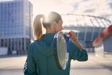 Orta yaşlı sporcu kadın, profesyonel tenisçi dışarıda tenis raketiyle dikilen, sabah antrenmanına hazır.