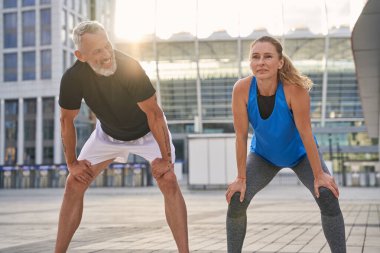 Aktif orta yaşlı çift, erkek ve kadın bir yaz günü şehirde birlikte koşmaya hazırlanıyorlar.