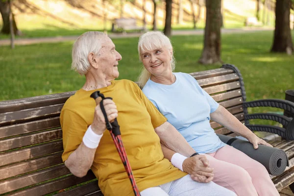 Fröhliche Senioren mit Sportgeräten ruhen sich auf Bank im Park aus — Stockfoto