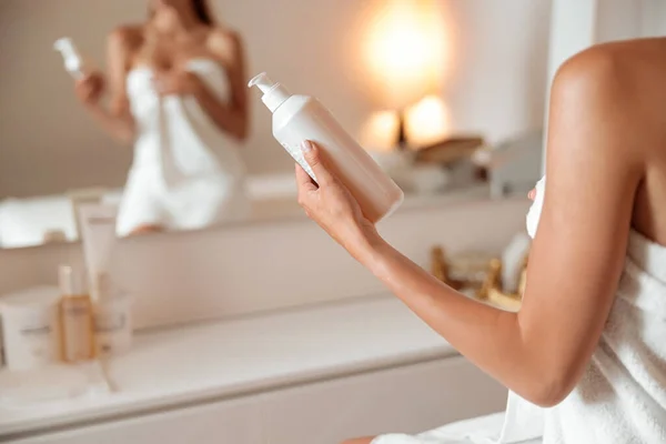 Mujer joven sosteniendo botella de crema cosmética o loción — Foto de Stock