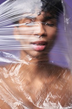 Kafasında plastik torba olan genç transseksüel bir adamın portresi. Trans cinsiyet modeli, nefes al.