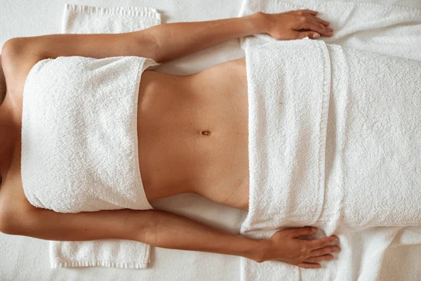 Fit young woman lying on massage table in spa salon — Stock Photo, Image