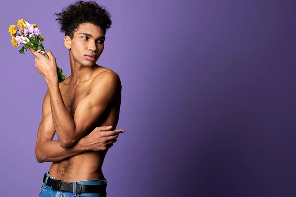 Portrait of latino transgender male model with bouquet on purple background. Young man nacked torso — Stock Photo, Image