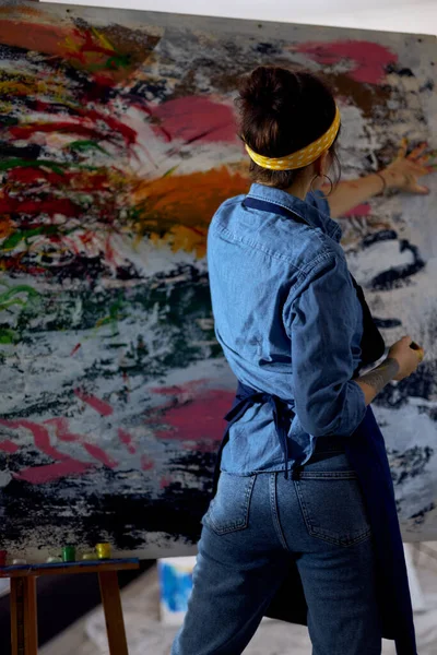 Vista posterior de la joven pintora creando una gran pintura al óleo abstracta moderna, la aplicación de pintura sobre lienzo con los dedos — Foto de Stock