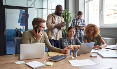 Birlikte proje üzerinde çalışıyoruz. Modern çalışma ortamında çalışırken iletişim kuran, konuşan, yeni fikirleri paylaşan çok ırklı çalışma arkadaşları.