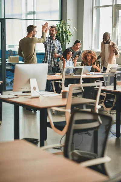 Hombres y mujeres jóvenes sintiéndose alegres y celebrando victorias de trabajo — Foto de Stock