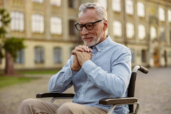 Portrait of pensive senior man pasien cacat di kursi roda tampak bijaksana sementara menghabiskan waktu sendirian di luar ruangan dekat klinik rehabilitasi — Stok Foto