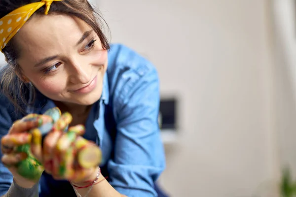 Close up portrait of pleased young woman, female artist with hands in colorful paint smiling aside — Stok Foto