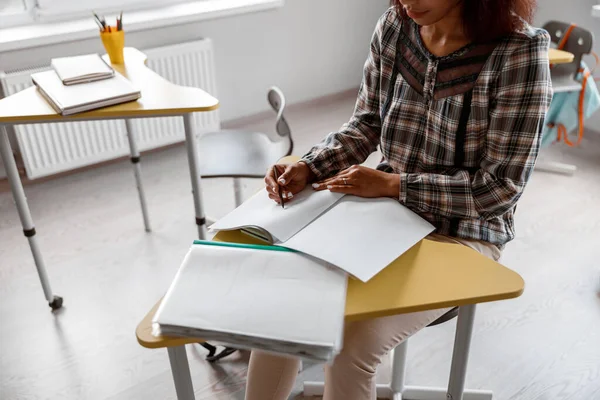 Teacher sitting at a desk and writing in a notebook — Stock Photo, Image