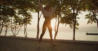 Canlı ve canlı bir dansçı, çarpıcı bir günbatımı arka planında özgürlüğün ve sevincin özünü bütünüyle somutlaştırır.