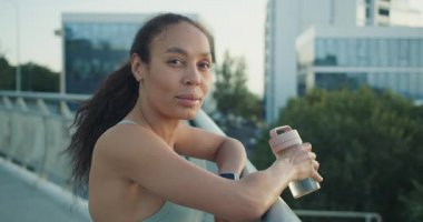 Sağlıklı bir kadın, canlı bir şehir zemininin ortasındaki güzel bir çatıda ferahlatıcı bir moladan zevk alır.