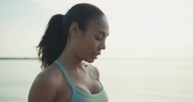 Bir kadın okyanus kıyısında farkındalık yapar, sükuneti somutlaştırır ve doğadaki güzelliğe odaklanır.