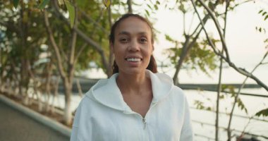 Beyaz ceketli neşeli bir kadın güzel ve manzaralı bir rıhtımın yanında huzurlu bir anın tadını çıkarıyor.