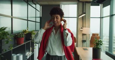 Fabrikada kulaklıklardan hoşlanan karaborsa yöneticisi gülümsemeleri ve rahat duruşu kapat, modern masa arkaplanı.