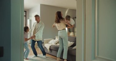 Kafkas ailesi evde sarılıp oynuyor, baba yürümeye yeni başlayan çocuğu kaldırırken anne, çocuk ve kız kanepenin yanında dönüyor, sıcak.