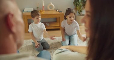 Gençler oyun becerilerini sergiliyorlar, çocuklar ailelerini eğlendiriyorlar ve halının üzerinde oyun oynuyorlar.