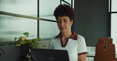 Dizüstü bilgisayardaki odaklanmış kadın, veri analisti raporları ve hesap tablolarını sakin bir konsantrasyonla inceliyor.