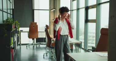 Açılış planının ofisinde neşeli jestler ve geniş bir gülümsemeyle ayakta duran kurucu telefon kulübesinin penceresinin yanında kutlama yapıyor.,