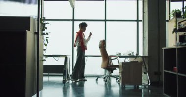 Siyah tasarımcı ofis sandalyesini pencere, tavan arası çalışma alanı bitkiler, masa ve yuvarlanan deri sandalye, güneş ışığı silueti,