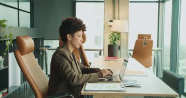 Bilgisayarda, düşünceli profilde, verileri ve mesajları kontrol eden, sessiz, modern ofiste çalışan profesyonel bir yazıcı.,