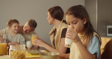 Genç kız cam içerken aile sohbetleri sakin sohbetler gevrek kasesi ve meyve suyu görünümlü aile gülümsemesi arasında yudumluyor.