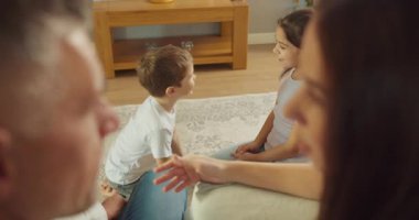 Kardeşler, eğlenceli oturma odası aktiviteleri sırasında dönüşümlü olarak oyun oynarlar ve ebeveynler mutlu bir şekilde gözlemlerler.