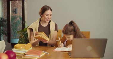 Anne ve kızı, masada başarıyı, neşeli moralleri kahkahalar ve gülücüklerle, ev ödevlerini bitirerek kutluyorlar.