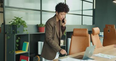 Karaborsa yöneticisi dizüstü bilgisayarda yazı yazmakla ve çizimler ve çizelgelerle belgeleri taramakla meşgul.,