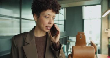 Yoğun siyahi girişimci, modern ofis masasına acil çağrı yapıyor. Endişe ve kararlılık gösteren ifadesel yüz ifadesi var.