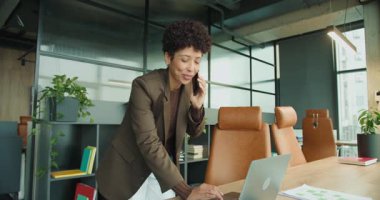 Ofis masasında cep telefonuyla kutlama yapan neşeli siyah kurucu, dizüstü bilgisayar ve çizelgeler, gülüyor ve gülümsüyor, neşeli başarı enerjisi.