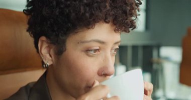 Düşünceli yüzün kahveyi yudumlaması, pencereye içsel bakış, hassas dudak hareketi ve sessiz duraksama, yumuşak sinemasal duraklama.