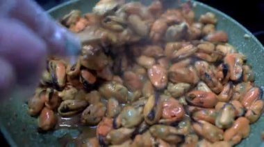 Midyeler tavada kızarır. Şef, midyeleri ahşap spatulayla karıştırır. HD