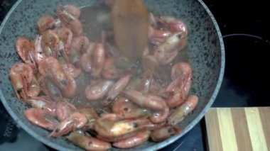 Karidesler tavada kızartılır. Şef karidesleri ahşap spatulayla karıştırır. HD