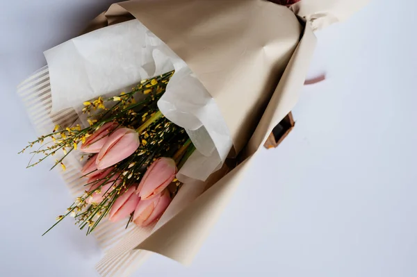 Beyaz arka planda bej pakette pembe laleler..