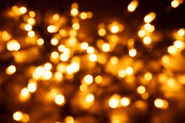 Garland glowing with warm light in dark. The atmosphere of the Christmas holidays. Overlay with golden bokeh.