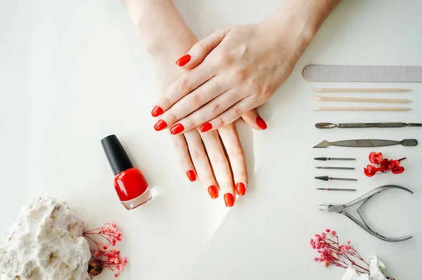 Manicured woman\'s nails with red nail polish. Tools of a manicure set on a white background.