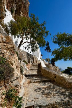 Amorgos Yunanistan - 09 Eylül 2025: Chozoviotissa 9. yüzyıl manastırına giden yol, Ege Denizi 'nin nefes kesici manzarasına sahip bir kaya yüzeyine inşa edilmiş bir mimari mücevher.