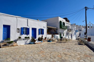 Amorgos, Yunanistan - 11 Eylül 2025: Chora Town 'da beyaz binalar, restoran ve ortodoks kilisesi bulunan kaldırımlı cadde