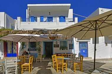 Amorgos, Yunanistan - 10 Eylül 2025: Ege Denizi 'ndeki muhteşem bir Cycladic adası olan Amorgos' taki Lagkada dağ köyünde servis servisi ve renkli açık hava sandalyeleri ve masaları olan küçük güzel bir restoranda bilinmeyen bir adam