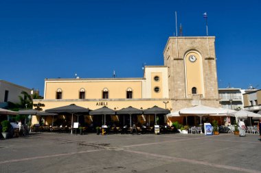 Kos, Greece - September 16, 2025:  Unidentified people on Eleftherias Square with the building Casa del Fascio - former house of the Italian fascists now used as cinema