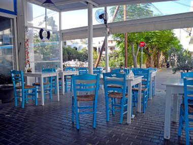 Kos, Greece - September 16, 2025: Fish shop with traditional white and blue tables and chairs, with an attached small restaurant where customers can eat the fish they have purchased.