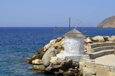 Amorgos, Yunanistan - Aigiali limanındaki iskelede arka planda mavi Ege Denizi olan küçük bir yel değirmeni manzarası.