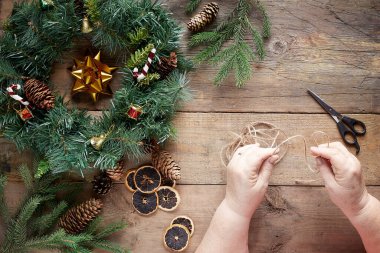 Tahta arka planda Noel çelengi. Büyükanne elleri.