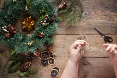 Tahta arka planda Noel çelengi. Büyükanne elleri.