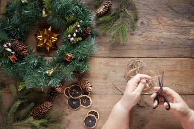 Tahta arka planda Noel çelengi. Büyükanne elleri.