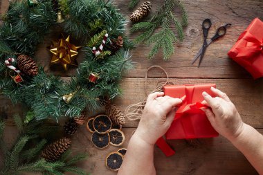 Tahta arka planda Noel çelengi. Büyükanne elleri.